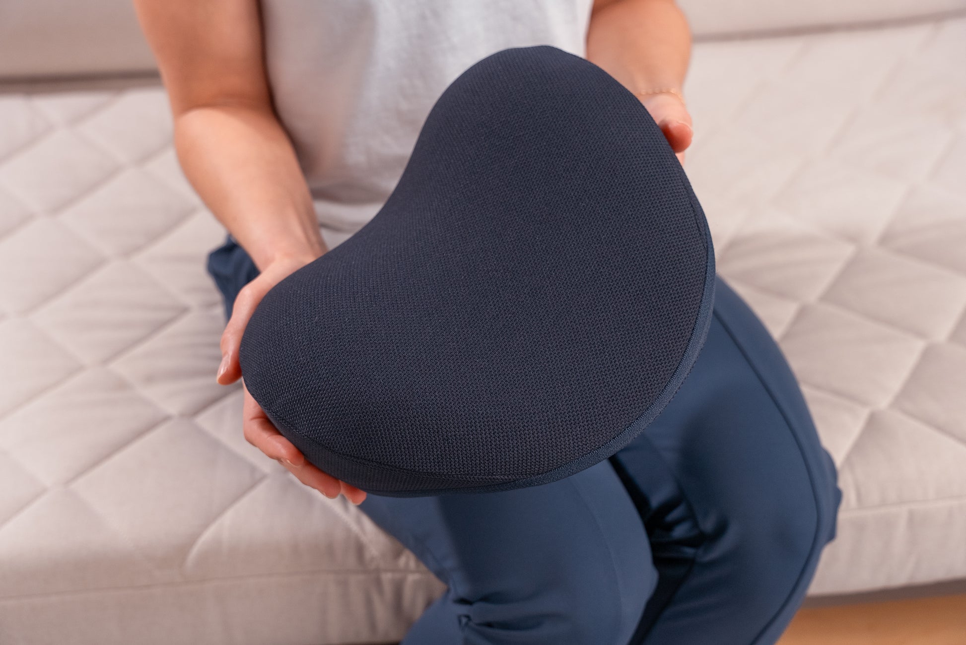 Model holding the HALO Neck Stretch Pillow in hands to show size and scale.