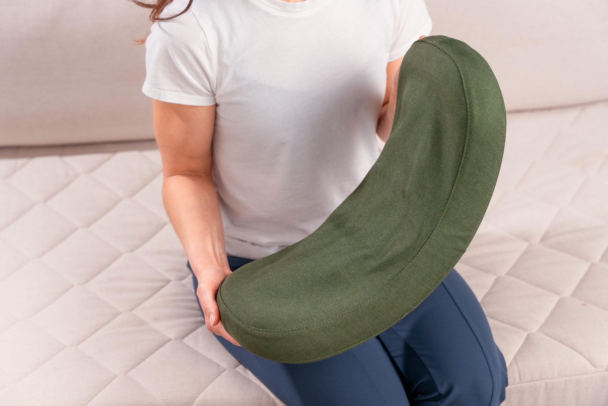 Female model holding the HALO Lumbar Stretch Massage Cushion in her hand to show the size and scale of the product.